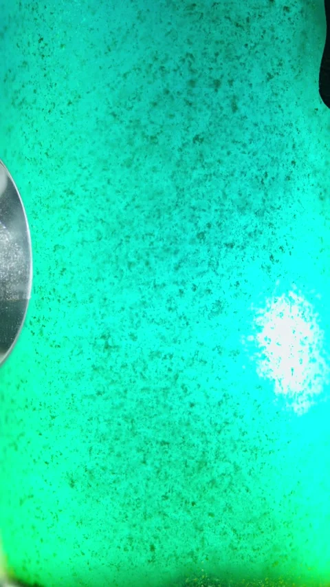 Close-up of a dirty turquoise-green liquid with dense suspended dark flakes Stock Footage 340637979