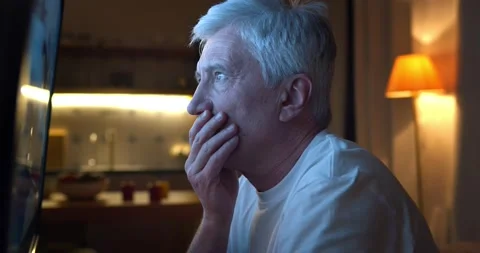 Close up of disappointed aged man watching tv news sitting near screen Stock Footage 147398281