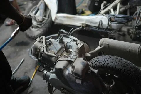 Close-Up of a Dismantled Motorcycle Engine on a Workshop Floor 스톡 사진