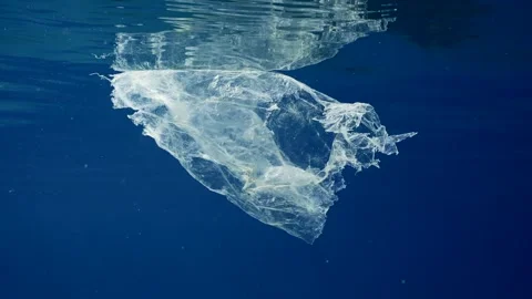 Close up of disposable plastic bag floating in blue sea, Slow motion. Stock Footage 243444420