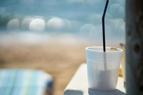 Close-up of a disposable plastic cup with a straw standing by the sea Stock Photos