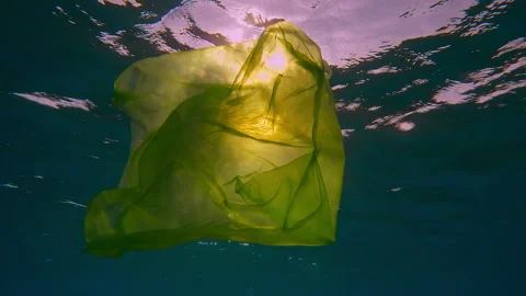 Close-up of disposable yellow plastic bag slowly drifting below water surface in Stock Footage 292144800