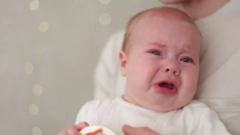 Close-up of a distressed baby crying with blue eyes and open mouth Stock Footage 340586990