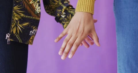 Close up of diverse couple holding hands on purple background Stock Footage 340986030