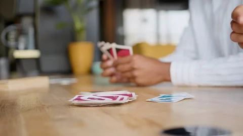 Close-up of diverse team hands engaging in a fun card game on a wooden office Stock Footage 335747094