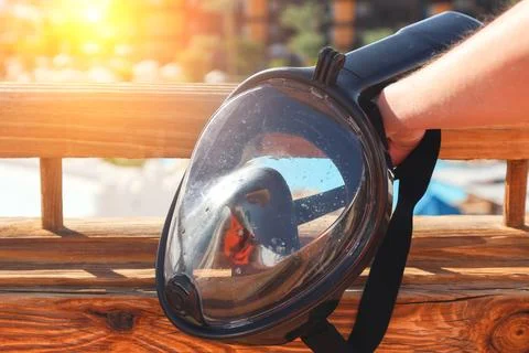 Close-up of a diving mask held in a woman's hand, ready for underwater advent Stock Photos