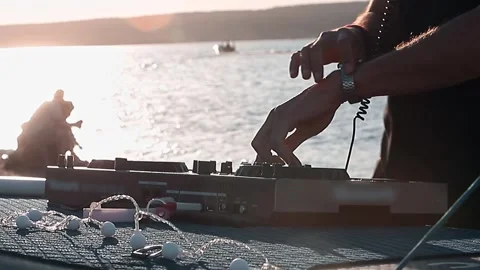 Close-up of DJ hands mixing on controller on at sunset Stock Footage 337785964