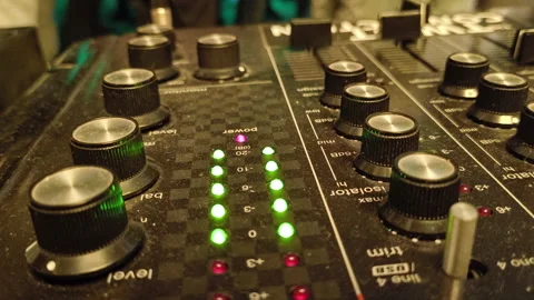 A close-up of a DJ mixer, showcasing a labyrinth of knobs and buttons bathed in Stock Footage 300537746