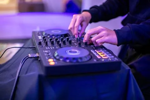 Close-up of a DJ's hands operating a modern digital DJ controller with illu.. Foto stock