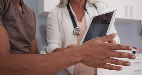 Close up of doctor explaining x-ray and cause of pain to male patient Stock-Footage 98417571