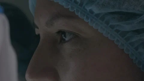 Close-up of a doctor with a focused look in the operating room, wearing a blue Stock Footage 301759890