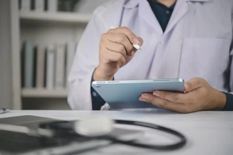 Close up doctor hands using digital tablet stylus pen writing hospital desk.. Stock Photos