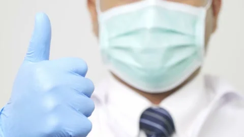 Close up doctor in uniform put on a face mask thumb up with blue glove on isolat Stock Footage 144650993
