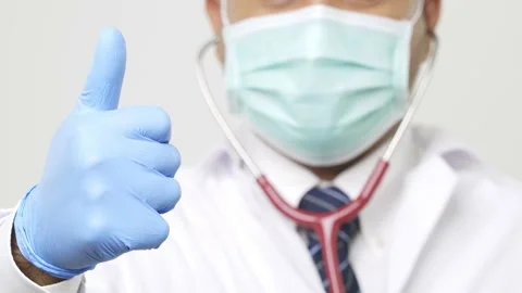 Close up doctor in uniform put on a face mask and stethoscope thumb up with blue Stock Footage 144651040