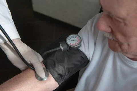 Close-up of a doctor using a stethoscope on an elderly person's elbow to meas Stock Photos