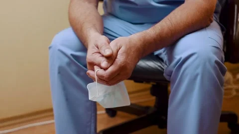 Close-up of the doctor's folded hands holding a medical mask. The camera Stock Footage 256157767