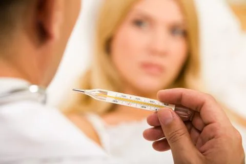 Close-up of doctors hand holding thermometer with sick woman on background Stock Photos