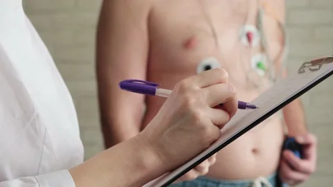 Close-up doctor's hand writing in patient's chart. Holter monitoring. Stockbeeldmateriaal 236342319