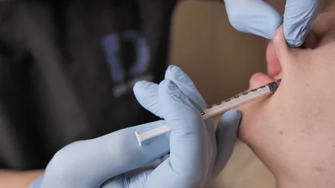 Close-up of a doctors hands in a blue gloves holding syringe and giving locak Video stock 123548479