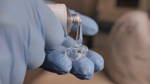 A close-up of doctor's hands in blue gloves holding a tube with transparent gel Stock Footage 124619176