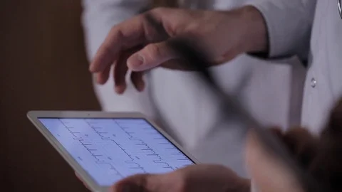 Close-up of doctor's hands, considering the patient's cardiogram on the tablet Stock Footage 71968865