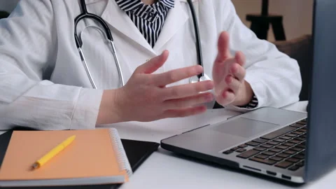 Close up of doctor's hands gesturing while talking to patient video call laptop Видео 235154374