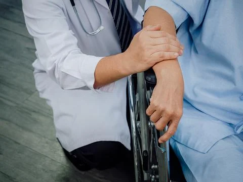 Close Up doctor's hands holding elderly patient 's hand in a wheelchair. Male Foto stock
