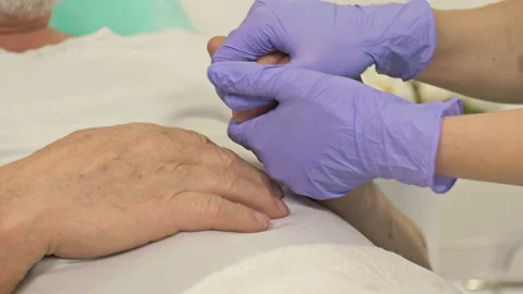 Close-up. Doctor's hands holding hands of an elderly patient. Support gesture. Stock Footage 148749300