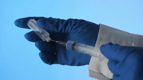 Close-up of a doctor's hands preparing a vaccine for injection on a blue Stock Footage 195247213