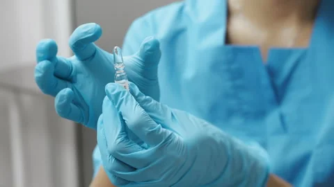 A close-up of a doctors hands preparing a vaccine vial for injection. Stock Footage 318942548
