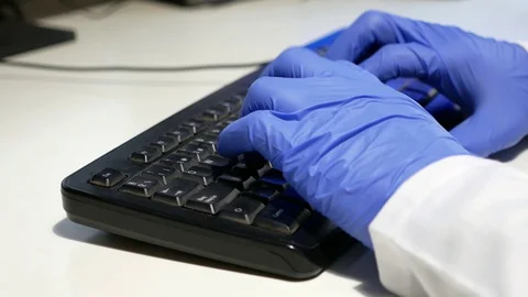 Close up of doctor's hands wearing nitrile gloves using a computer keyboard. Stock Footage 128323721