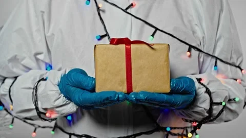 Close-up of doctor'shands in protective suit and blue gloves with gift box Stock Footage 143531484