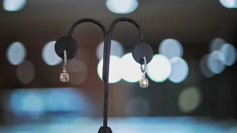 Close up dolly left diamond silver earrings on stand bokeh BG 4K Stock Footage 169093866