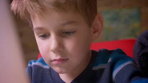 Close-up dolly shot of cute small boy working with laptop being concentrated at Stock Footage 108108547