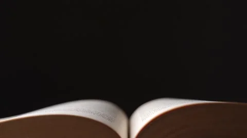 Close up dolly shot over an old open book with isolated black background Stock Footage 147344295