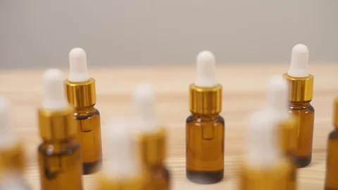 Close-up dolly shot passing small amber bottles with white caps Stock Footage 103134622
