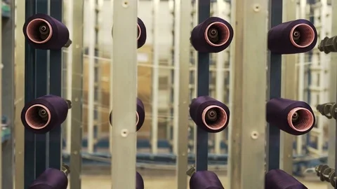 Close up dolly shot of purple spools of thread for sewing in textile fabric. Video stock 74752100