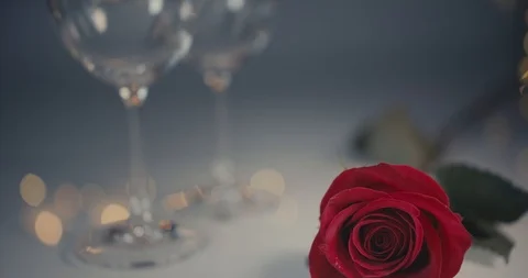 Close-up dolly shot. A single red rose. Two glasses of are beng filled with Stock Footage 100875242
