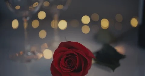 Close-up dolly shot. A single red rose. Two glasses of are beng filled with Stock Footage 100875246