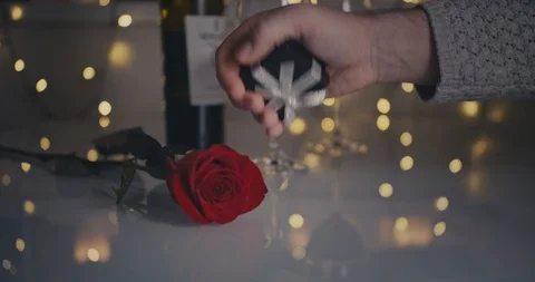 Close-up dolly shot. A small gift box is given by a male hand to a female and Stock Footage 100875257