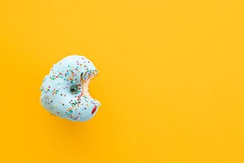 Close up donut with bite missing isolated on yellow background Foto stock