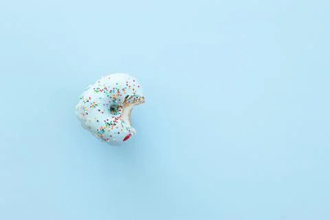 Close up donut with bite missing isolated on blue background Stock Photos