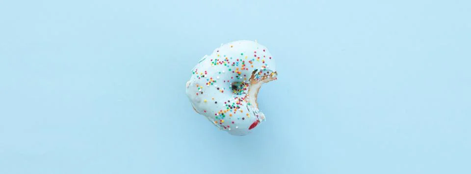 Close up donut with bite missing isolated on blue background Foto stock