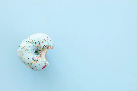 Close up donut with bite missing isolated on blue background Foto stock