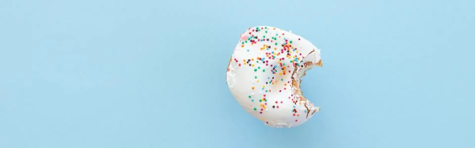 Close up donut with bite missing isolated on color background Stock Photos