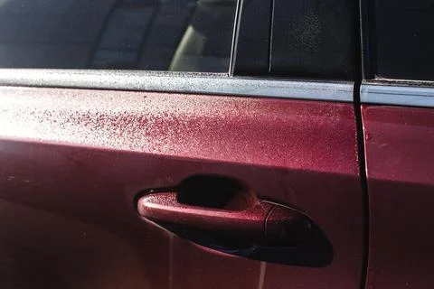 Close-up of a door handle of a maroon colored car, after the rains. Stock Photos
