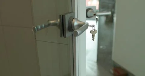 Close-up of a doorknob with a key inserted. Close-up of open transparent gl.. Stock Photos