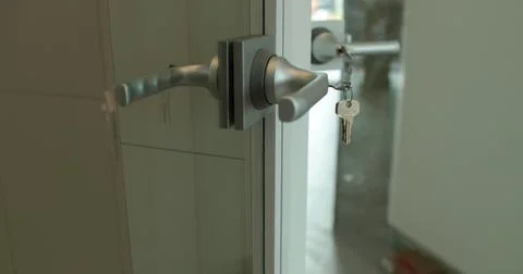 Close-up of a doorknob with a key inserted. Close-up of open transparent gl.. Stock Photos
