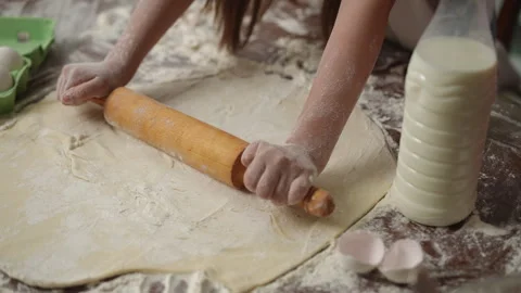 Close-up of the dough on the table, which a girl tiredly rolls out with a Stock Footage 257050952