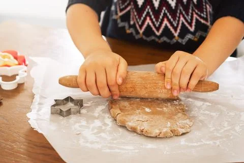 A close up dough.Child hands using rolling spin for gingerbread cookies Foto stock